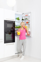 Fototapeta na wymiar woman drink orange juice hold glass refrigerator