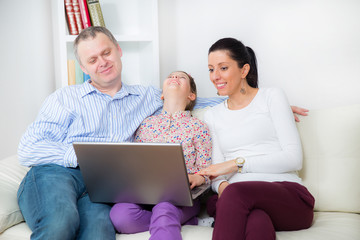 Fototapeta premium Family sitting on the sofa and looking at laptop
