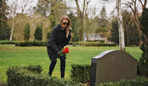 Woman at the cemetery paying respects with fresh flowers