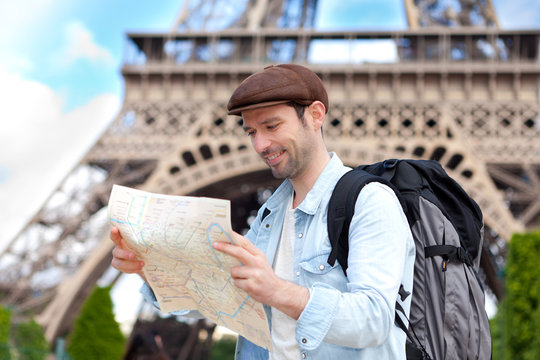 Young attractive tourist reading map in Paris