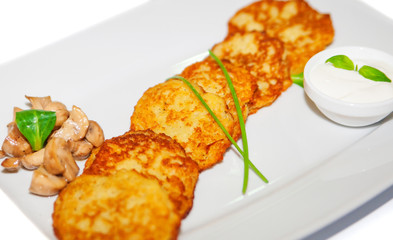 Potato pancakes with sauce and mushroom on plate, restaurant