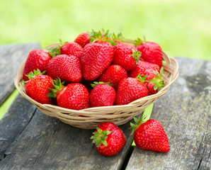 basket with strawberries on a garden wooden table