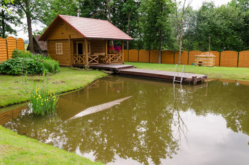 Fototapeta na wymiar new rural bathhouse and pond with plank footbridge