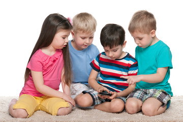 Kids with a gadget on the carpet