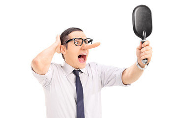 Furious man with long nose looking in a mirror