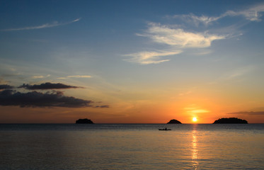 Kayakers silhouette on ocean during orange sunset