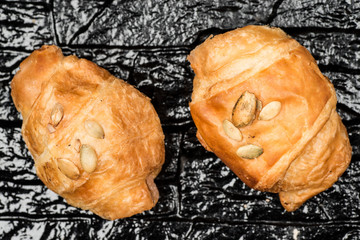 Top view of two croissants over a black shiny background