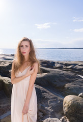 Fototapeta na wymiar Young woman on rocky shore