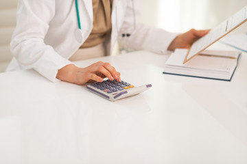 Closeup on medical doctor woman using calculator