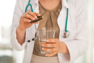Closeup on medical doctor woman dripping calmative into glass