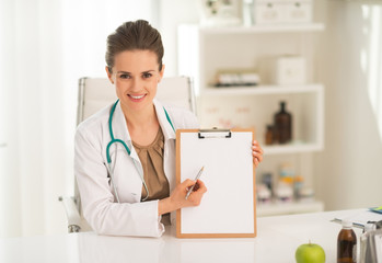 Happy medical doctor woman pointing in clipboard