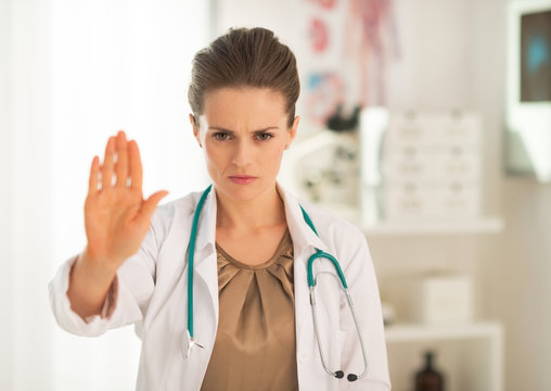 Portrait of serious medical doctor woman showing stop gesture