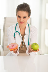 Medical doctor woman giving a choice between apple and donut