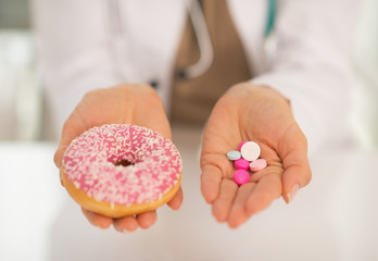 Closeup on medical doctor woman showing donut and pills