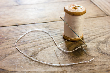 coil with white threads and a needle stuck