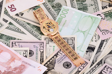 stack of 100 dollar bills and gold watch on a full background