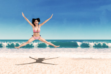 Woman wearing swimsuit jumping on beach