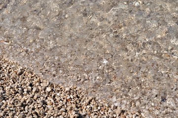 Clear water with beach pebbles. Natural background