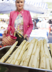 Frau kauft Spargel auf dem Wochenmarkt