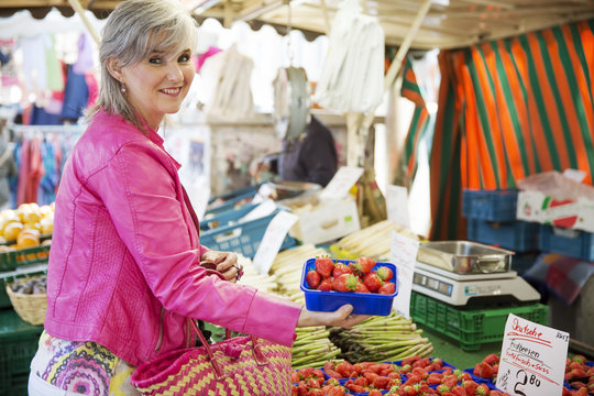 Frau kauft Erdbeeren auf dem Markt,