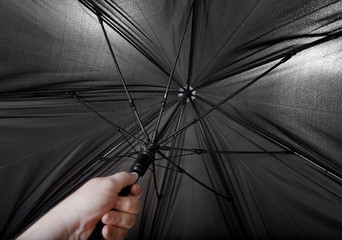 hand opens big black umbrella