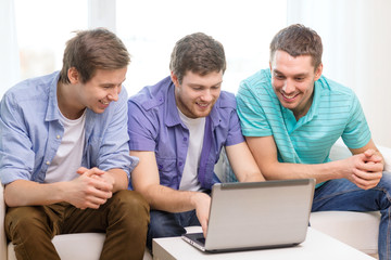 smiling friends with laptop computer at home