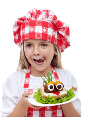 Happy little girl with chef hat and creative sandwich