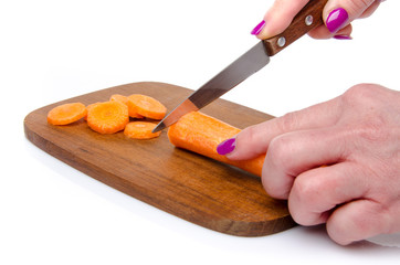 Woman's hand slicing a carrot on a wood cutting board