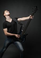 Fototapeta premium young male musician playing a six-string bass guitar isolated on