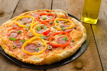 Italian pizza with paprika, salami and olives