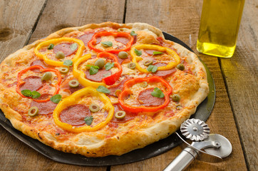 Italian pizza with paprika, salami and olives