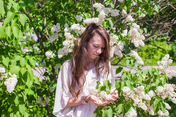 Young beautiful woman in white lilac garden enjoy spring day