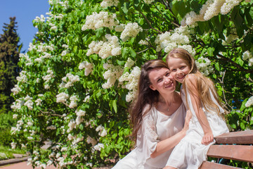 Happy mother and adorable girl enjoying warm day in lush garden