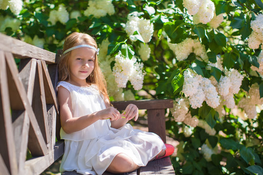 Adorable happy little girl have fun in flower blossoming garden