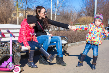 Young mother and little happy girls enjoy sunny day in the park