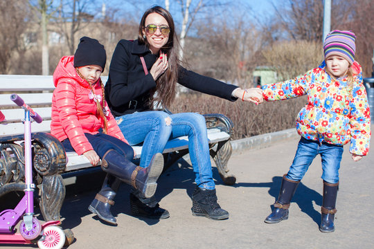 Happy mother and little girls enjoy sunny day in the park