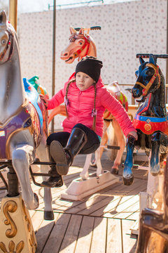 Little happy girl on carousel at an amusement park