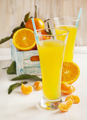 Glass of Citrus juice and fresh oranges and mandarines in rustic