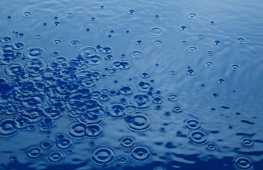 Rain drops rippling over blue background