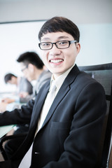 Businessman smiling at the camera while his team is working in t