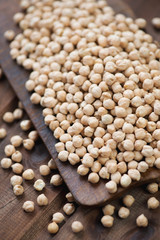 Rustic wooden cutting board with raw chickpeas, vertical shot