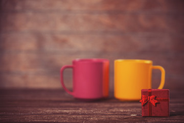 Little gift and two cups on background.