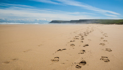 Footprints of hiking boots on the sand of a remote beach in Scot