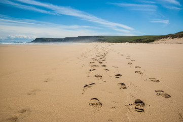 Footprints of hiking boots on the sand of a remote beach in Scot