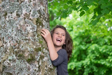 Fotobehang Happy laughing Girl holding big tree © coldwaterman