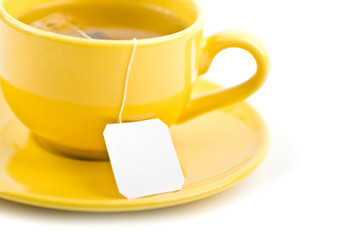 Cup of tea with tea bag (blank label) on white background