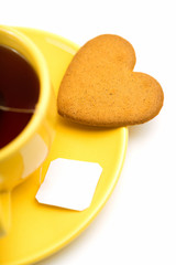 yellow cup with tea bag and heart-shaped cookie