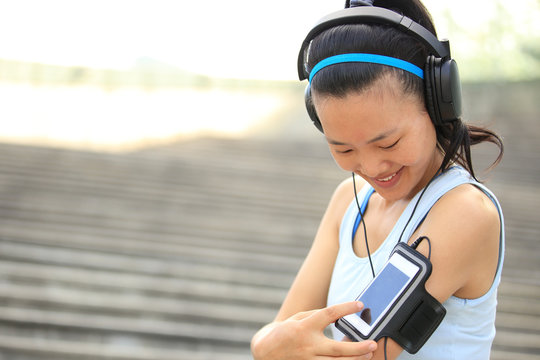woman unner listening to music in headphones from smart phone