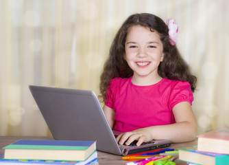 Smiling school girl with laptop at desk