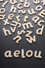 Wooden letters spell aeiou on a blackboard